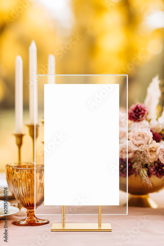 Acrylic sign mockup placed on a luxurious wedding reception table with candles, golden glassware, and floral centerpiece in a warm, festive atmosphere