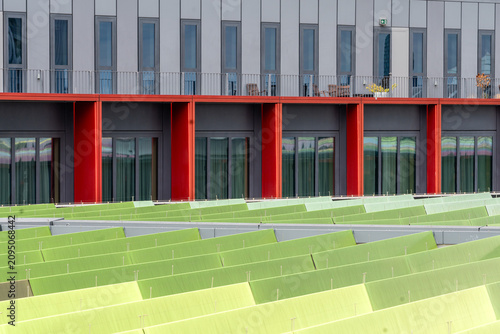 Foto Ansicht moderner Architektur mit markanten roten Stützelementen und einer gestuften grünen Oberflächenstruktur