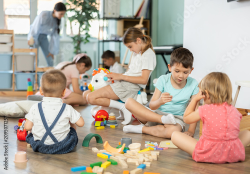 Foto Toys are scattered on floor, children are playing with cubes and cars