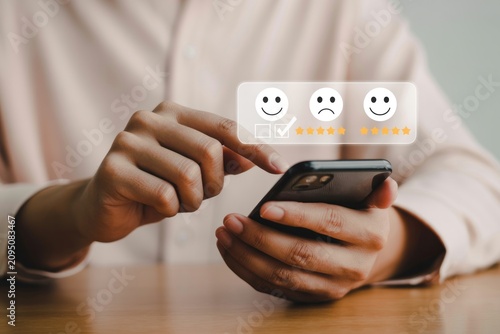 Person giving feedback on smartphone with rating emojis and stars on screen displayed