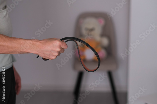 Man holding leather belt for punishment. 