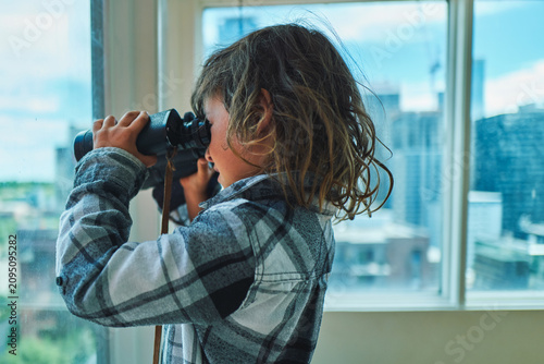 Fotografie Boy looking through binoculars - side profile with warm backlight