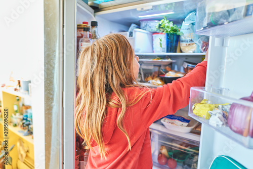 Foto Boy reaching into a stocked fridge at home