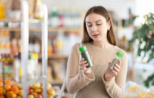 Girl shopping at supermarket - choosing ground pepper in grocery section