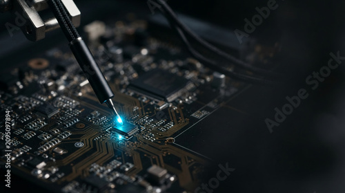 Microchip circuit board examination with glowing probe in electronics laboratory