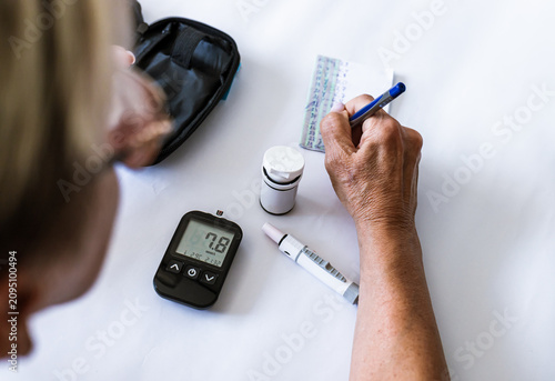 Tableau sur toile Woman recording blood glucose results after diabetes testing at home