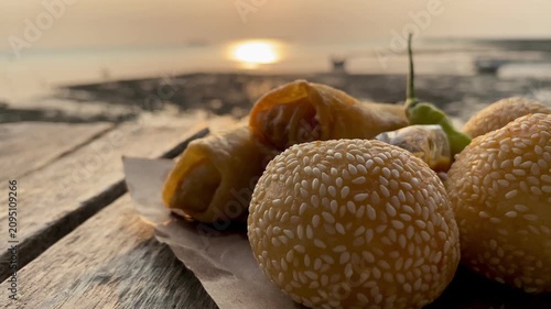 Traditional Indonesian fried snacks, sesame seed balls and crispy spring rolls on a wooden table