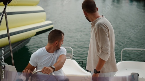 Foto Men steering a boat through a marina during a summer outing
