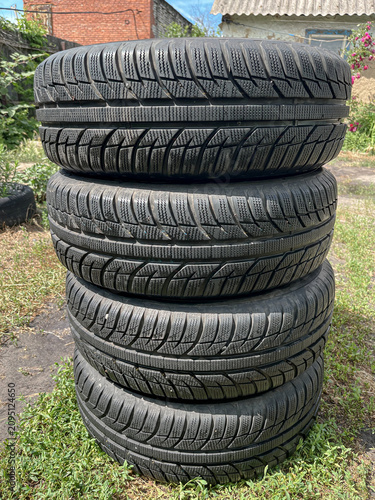 Foto Stack of four used winter car tires outdoors