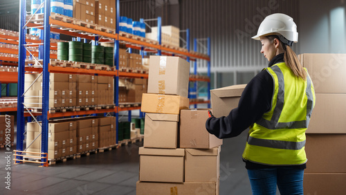 Canvastavla Warehouse operations, female warehouse worker inspecting and organizing cardboard boxes in storage aisle, logistics fulfillment center workflow