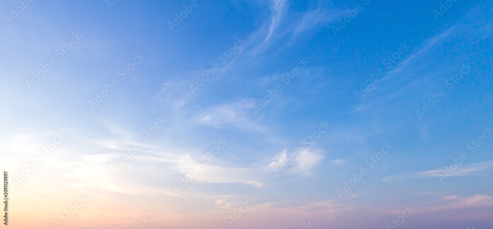 Fototapeta premium Beautiful clear blue sky background with soft pastel orange pink gradient light and wispy clouds for panoramic travel mockup design