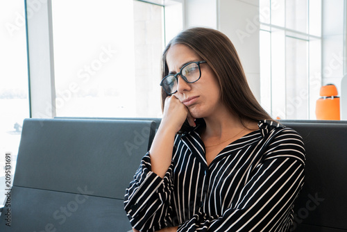 Fotografie Young frustrated woman with glasses leaning on hand, looking tired and bored whi