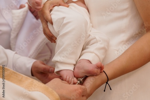 Fotografie Priest anointing infant baby during a baptism ceremony in a white dress with soft neutral lighting