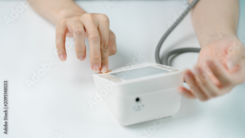 Photos Close-up of an adult pressing a digital blood pressure monitor before a home health check