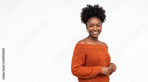 Young black woman smiling while standing in an orange sweater  