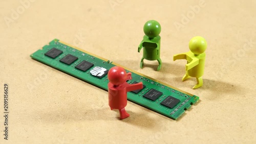 Three colorful toy figures gathered around a green desktop RAM module on beige surface, computer memory shortage, hardware supply crisis, teamwork, debate and rising component prices concept