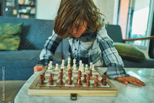 Photography Boy concentrating over a chess board at home