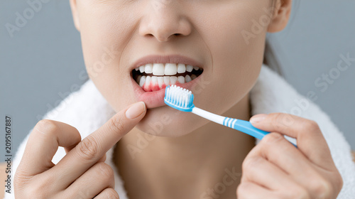Young woman looking at her red bleeding gums
