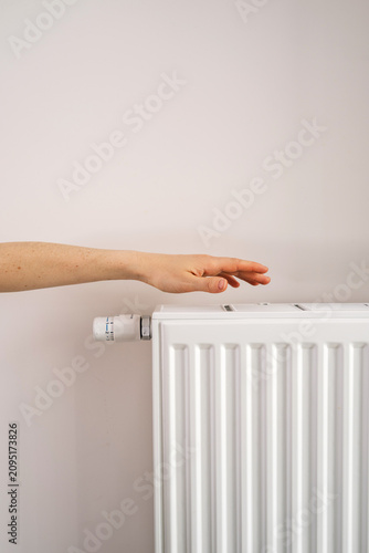Foto Hand reaching toward home heating radiator in modern apartment room