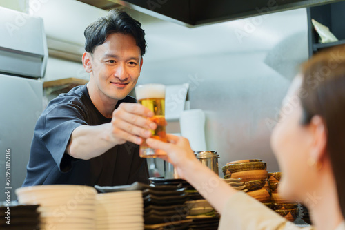 居酒屋でお客様にビールを提供する店長
