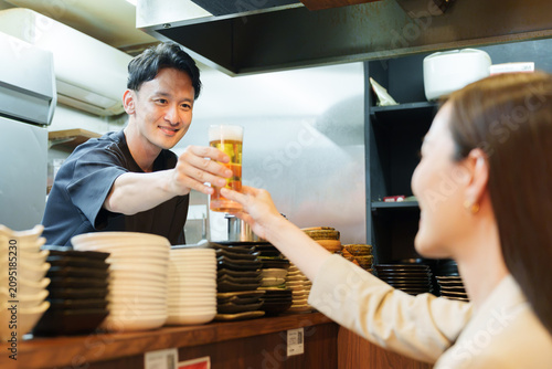居酒屋でお客様にビールを提供する店長