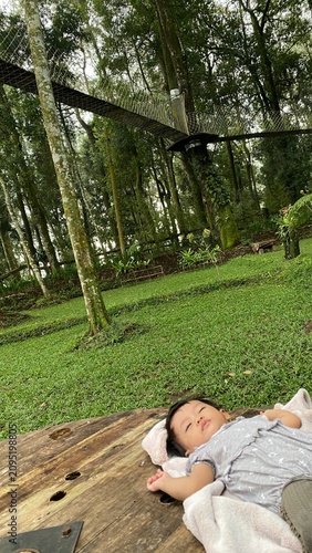 Cute baby sleeping peacefully on a wooden table in a green forest park
