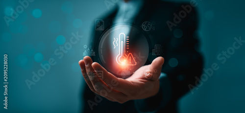 Climate risk management concept with business hand holding virtual heat warning interface showing thermometer icon global warming impact urban safety and environmental monitoring
