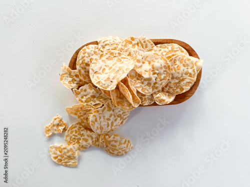 Cuadro en lienzo Crispy tempeh chips spilling from wooden bowl, overhead view