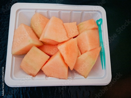 Obraz na plátně Close up of juicy orange rockmelon pieces with a small plastic fruit fork