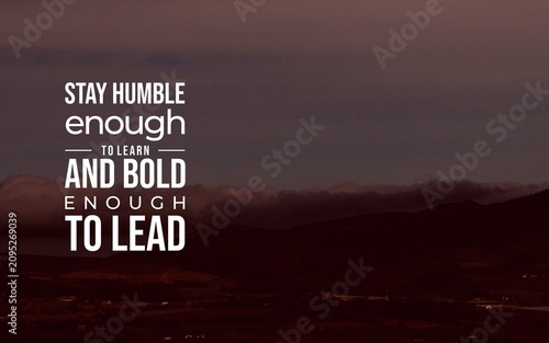 Motivational quote about staying humble enough to learn and bold enough to lead, set in clean typography over a warm mountain landscape.