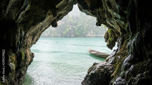 Scenic Tropical Cave View of Traditional Boat on Turquoise Water with Limestone Cliffs and Misty Rainforest Backdrop, Website Banner, Hero Header, Wide Background