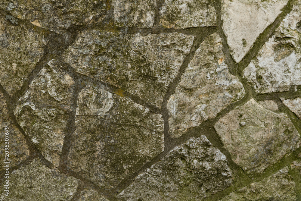 Fototapeta premium Old Weathered Stone Wall Texture Background Rustic Aged Surface with Mossy Patches for Architecture and Construction Concepts
