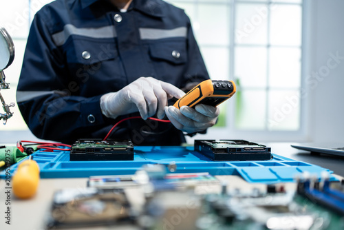 Fotografía Technician in gloves tests computer hard drives with a handheld meter at an elec