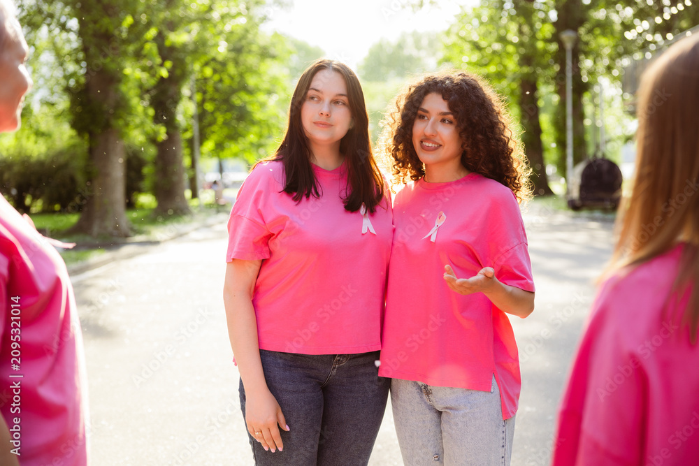 Fototapeta premium Group of diverse smiling women wearing pink t shirts supporting breast cancer awareness on street