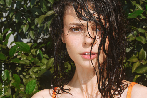 Cuadro en lienzo A woman portrait with wet hair and dewy skin stands among lush greenery, sunlight catching the natural textures of her skin