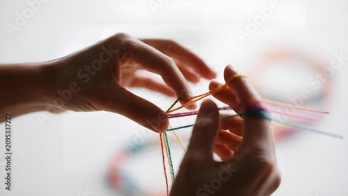 Hands weaving colorful threads to create a handmade friendship bracelet.