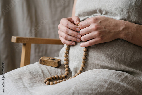 Expectant Mother Holding Wooden Prayer Beads During Quiet Meditation At Home