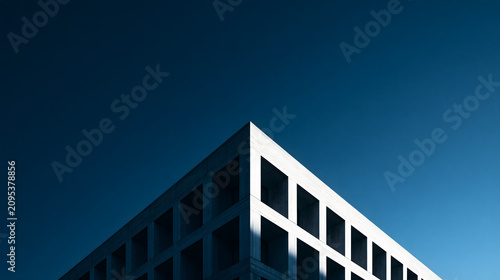 Low angle view of modern brutalist concrete building corner against a clear blue sky