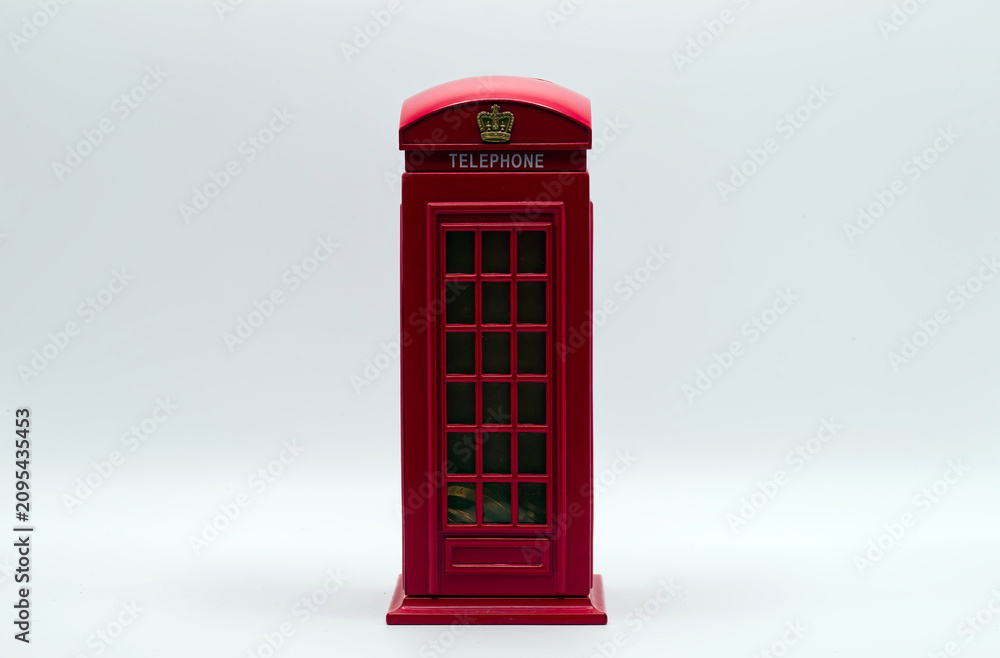 Obraz premium Red miniature model of a classic london telephone booth used as a money box on white background.