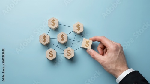 Hand placing a wooden block with a dollar sign to complete a financial network