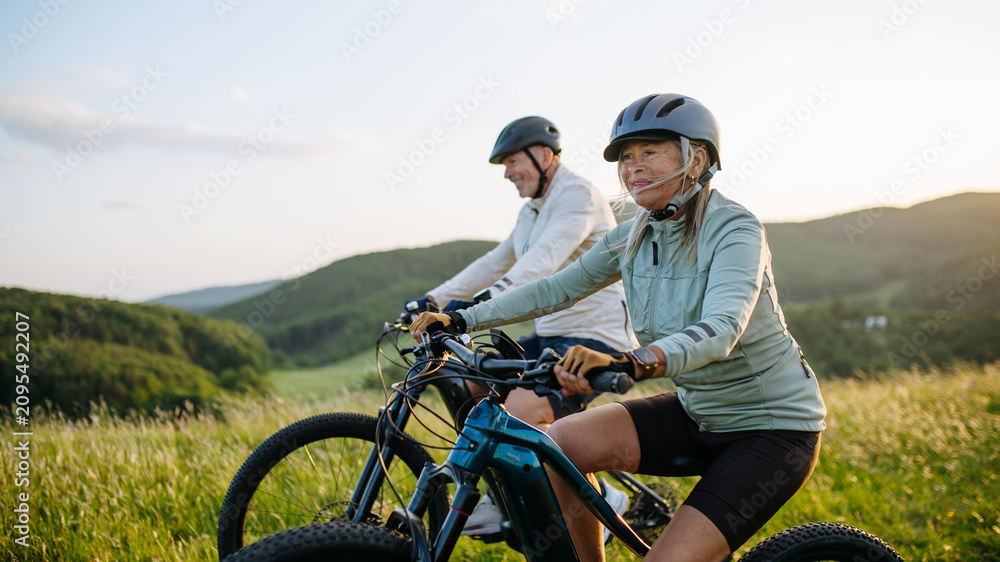 Fototapeta premium Active senior couple exploring nature on electric bicycles