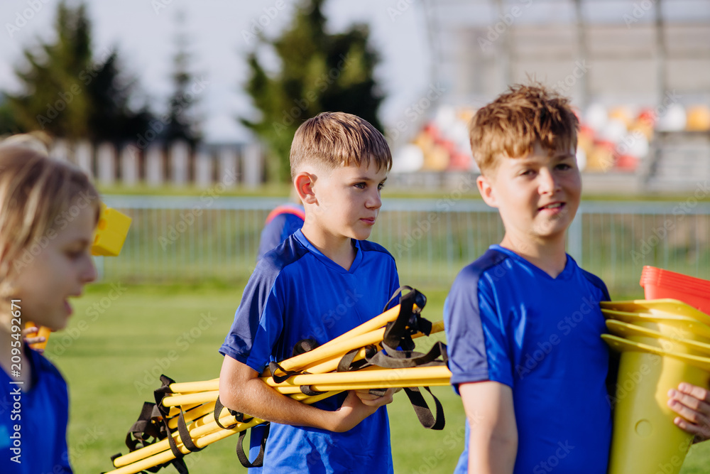 Obraz premium Children helping prepare football training session on sports field.
