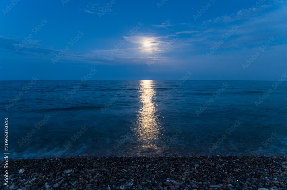 Obraz premium Moonlight reflection on sea water surface at dark beach night