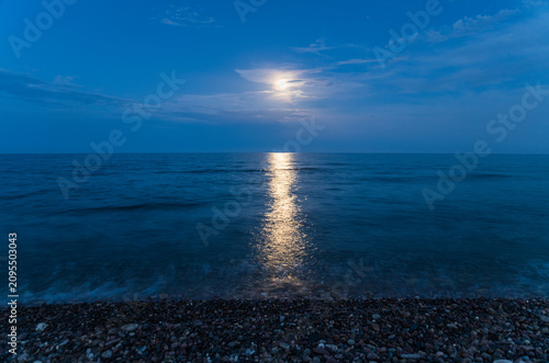 Moonlight reflection on sea water surface at dark beach night