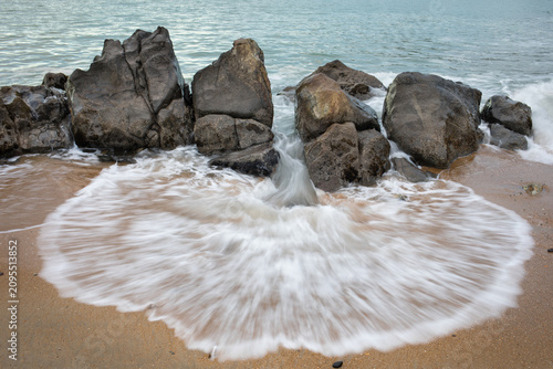 Obraz na płótnie Water washes ashore through rocks