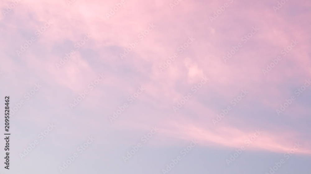 Obraz premium Soft, dreamy sunset sky featuring delicate, wispy pink clouds drifting across a tranquil, pale lilac-blue horizon.