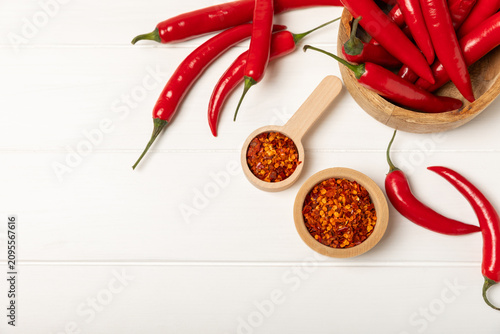Chili pepper and chili powder on a wooden table. Red hot natural chili pepper. Organic fresh chili pepper flakes and paprika powder in a bowl on the table. Spicy spices. Copy space. Space for text.