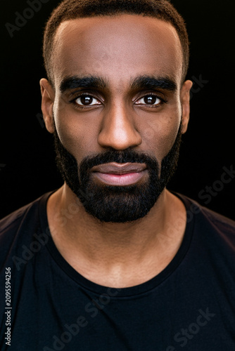 Close Up Portrait of Confident Black Man Wearing Black T Shirt on Dark Background