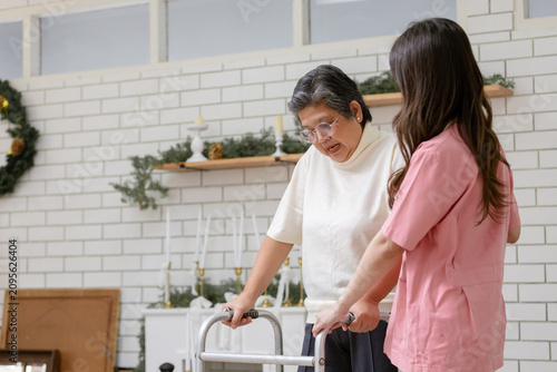 Quadro su tela Caring professional caregiver assisting Asian senior woman using medical walker