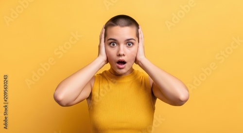 Shocked young woman with buzz cut holding her head with both hands